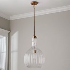 a glass light fixture hanging from a ceiling in a room with white walls and windows