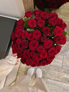 a bouquet of red roses sitting on the floor next to a person's feet