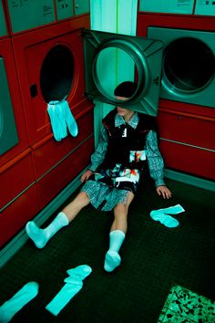 a woman sitting on the floor in front of a dryer with blue socks around her