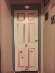 a white door with pink flowers painted on the front and side panels, in a hallway