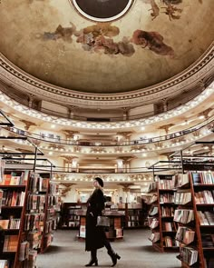 a woman standing in the middle of a library filled with books