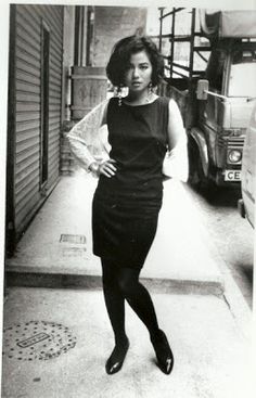 black and white photograph of a woman standing on the sidewalk