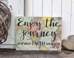 a sign that says enjoy the journey on it next to some rocks and a plant