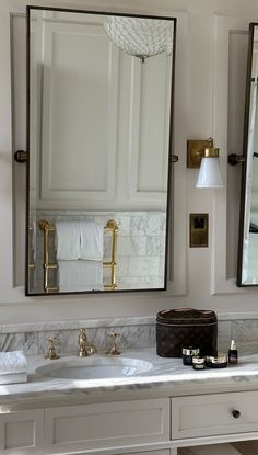 a bathroom vanity with two sinks and large mirrors on the wall above it, in front of a mirror