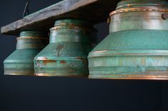 an old green light fixture hanging from a wooden beam