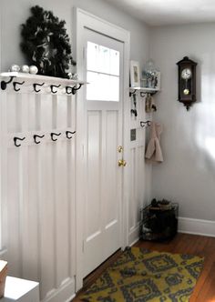 a white door with some hooks on it and a yellow rug in front of it