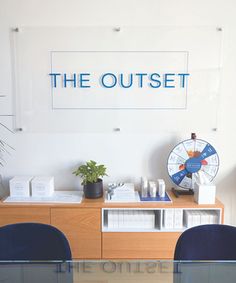 there is a glass table with blue chairs in front of the sign that says the outlet