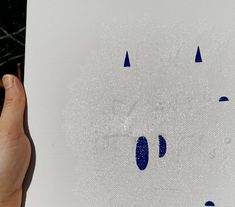 a person holding up a piece of paper with blue dots on it and an image of a cat's face