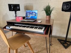 a laptop computer sitting on top of a wooden desk next to a keyboard and speakers