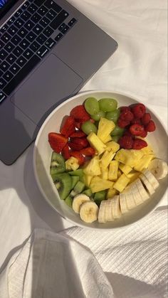 a white plate topped with fruit next to a laptop