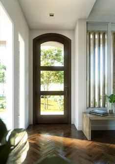 an open door leading into a room with wood flooring and windows on both sides