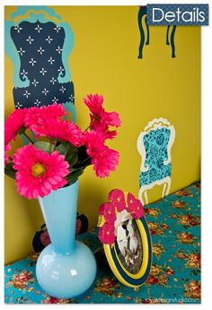 a blue vase filled with pink flowers on top of a table next to a mirror