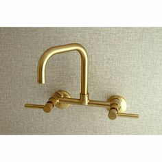 a gold faucet with two handles on the wall