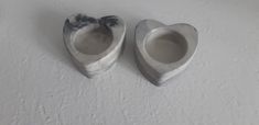 two heart shaped bowls sitting on top of a white wall