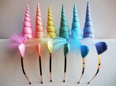 five different colored unicorn hair pins with feathers on them, all lined up in a row