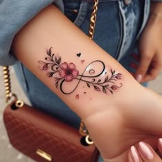 a woman's arm with a tattoo on it that has flowers and an infinite sign