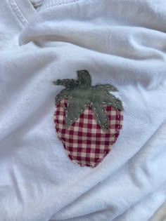 a close up of a strawberry patch on a white t - shirt with red and white checkered fabric