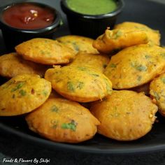 some food is on a black plate with dipping sauces