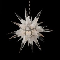 a white chandelier hanging from a chain on a black background in the shape of a snowflake