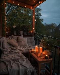 a porch covered in candles and blankets with flowers on the side table next to it