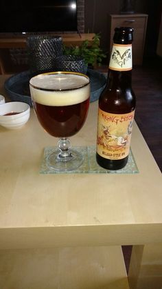 a bottle of beer and a glass sitting on a table in front of a bowl