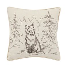 a pillow with a drawing of a fox sitting in front of some trees and snow