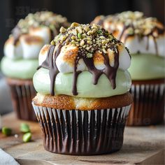 three cupcakes with green frosting and nuts on top