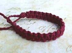 two red crocheted bracelets sitting on top of an old piece of paper