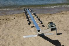 a boat trailer sitting on top of a beach next to the ocean with wheels attached