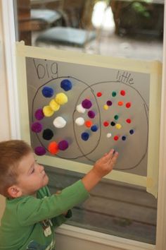 a young boy sitting in front of a white board with magnets and writing on it