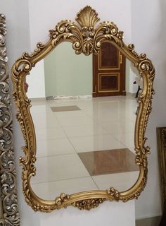 an ornate gold framed mirror sitting on top of a white floor next to a wall