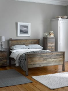 a bed sitting in a bedroom next to a wooden dresser and lamp on top of a hard wood floor