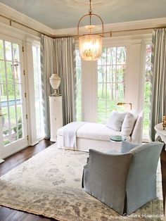 a living room filled with furniture and windows covered in drapes, along with a rug on the floor