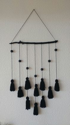 a group of black tassels hanging from a white wall next to a potted plant