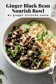 a bowl filled with rice, black beans and cucumber garnished with sauce