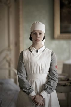 a woman in an apron standing next to a bed