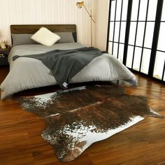 a bed room with a neatly made bed and cowhide rug