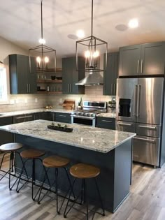 a large kitchen with stainless steel appliances and wooden stools in front of the island