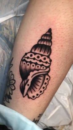 a close up of a person's leg with a tattoo on it and a sea shell