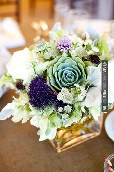 a vase filled with lots of flowers on top of a table next to a candle