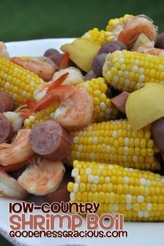 corn on the cob with sausage and shrimp is served in a white bowl outdoors