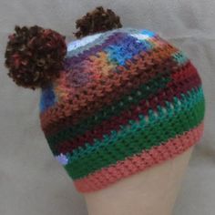 a multicolored knitted hat with two pom - poms on top