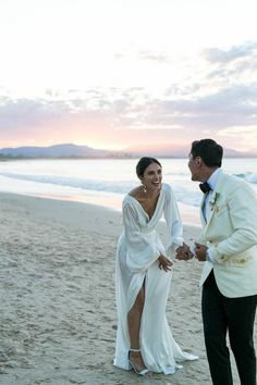 a newly married couple holding hands on the beach