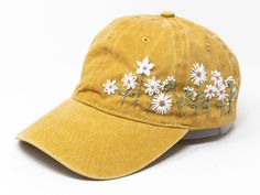 a yellow hat with white daisies embroidered on the front and back side, against a white background