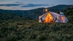 a yurt in the middle of a field with mountains in the background at night