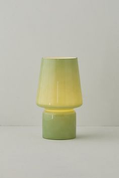 a yellow and green vase sitting on top of a white table