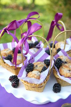 small baskets filled with blackberries and muffins on top of a white plate