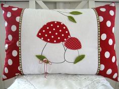 a red and white pillow sitting on top of a chair next to a table with a lace doily