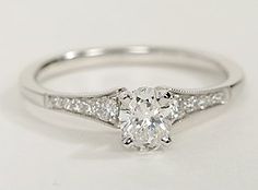 a white gold ring with diamonds on the sides and an oval shaped diamond in the middle