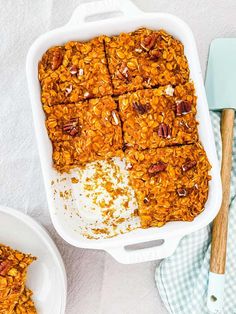 a casserole dish filled with granola and nuts next to a spatula